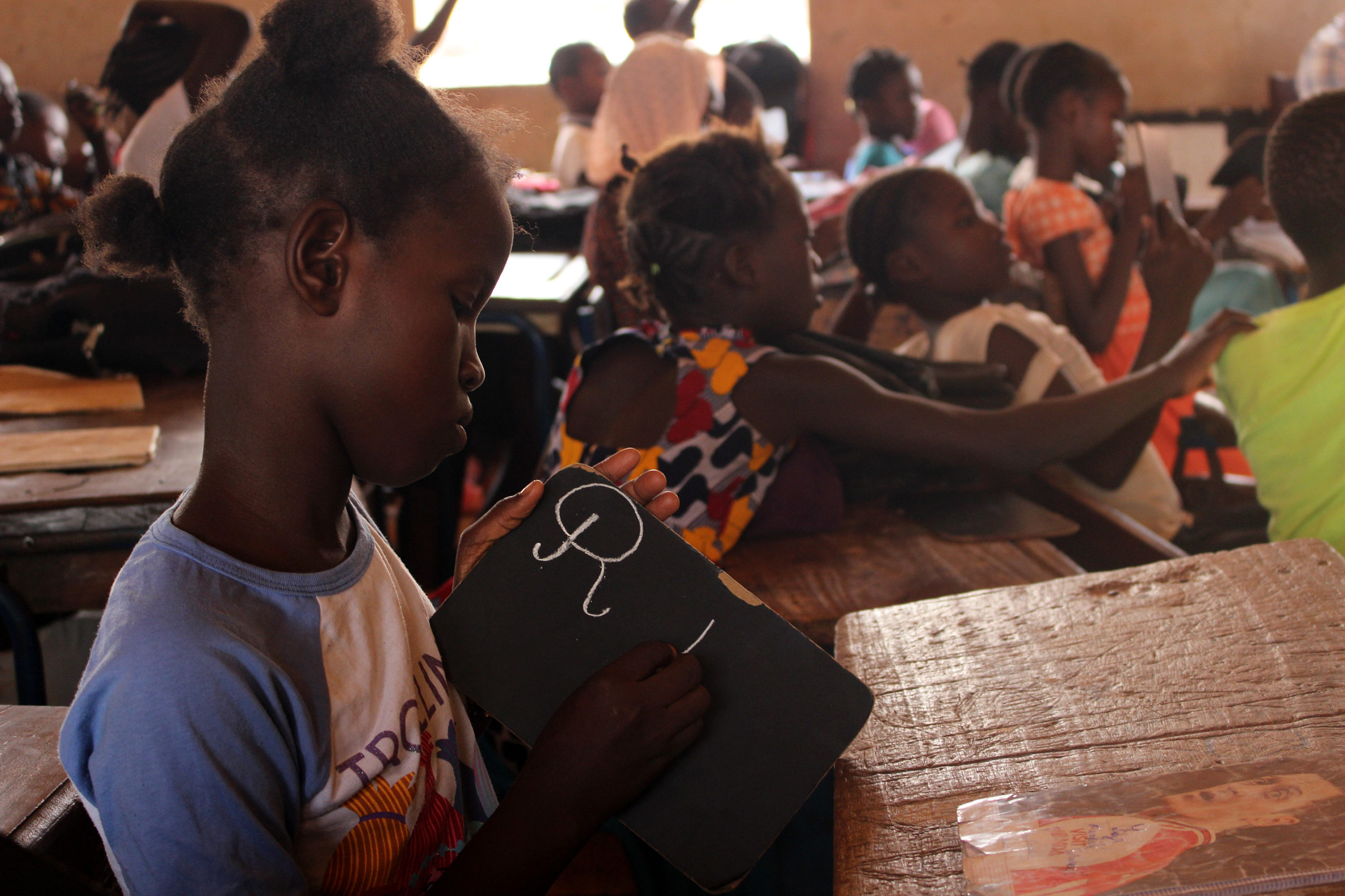 Una alumne a Mali escriu sobre una pissarra