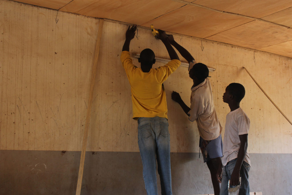 Tres treballadors arreglen el sostre d’una aula