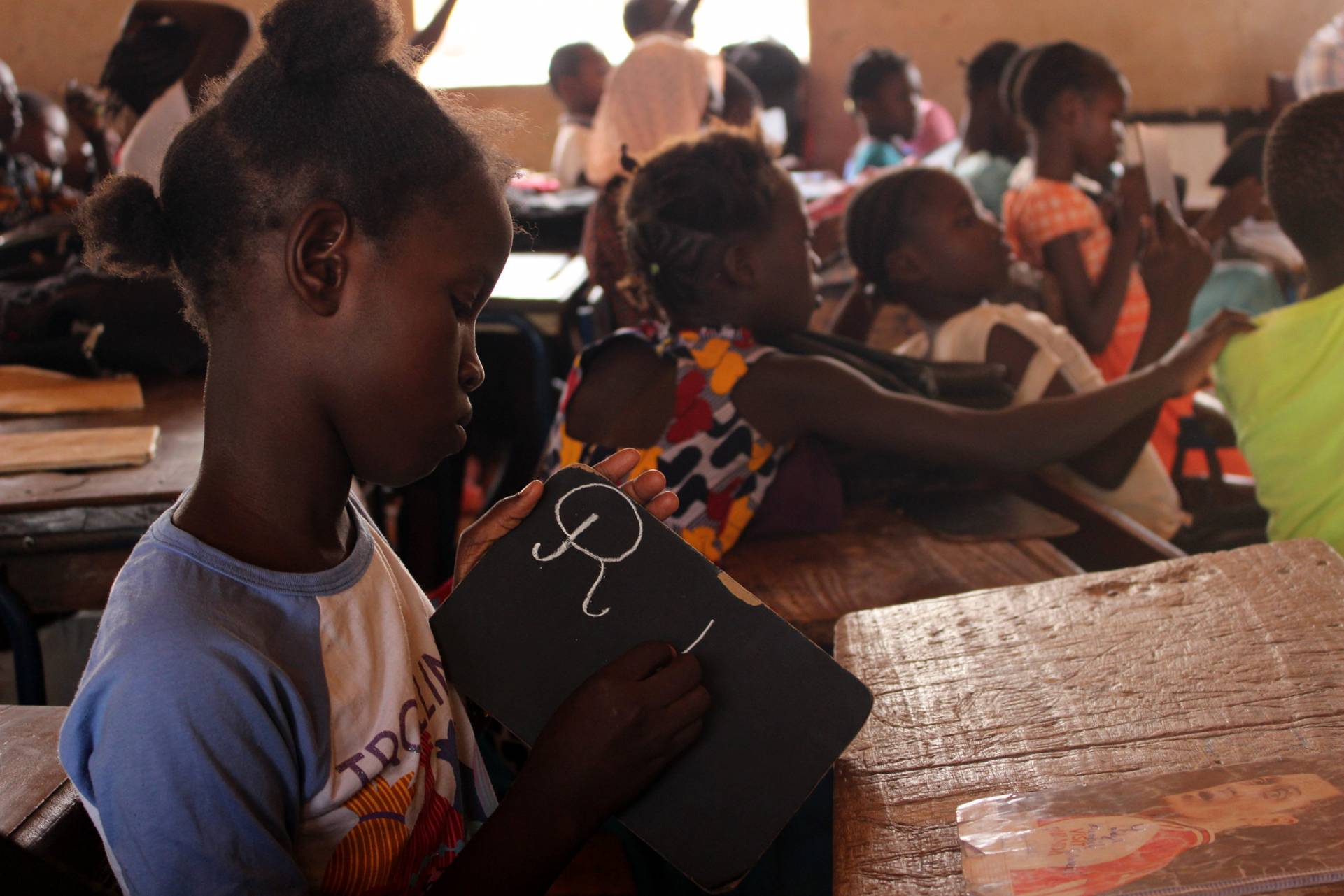 Una niña escribe en su pizarra en la escuela donde trabaja Djouma